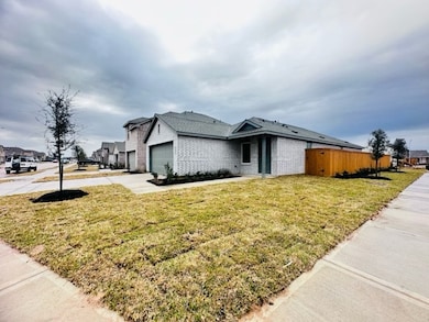 This is a modern, single-story home on a corner lot with a light brick exterior and a two-car garage. The yard is spacious and newly landscaped.