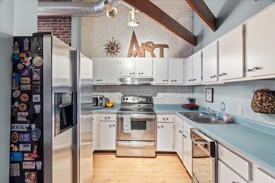 Kitchen featuring sink, white cabinetry, brick wal