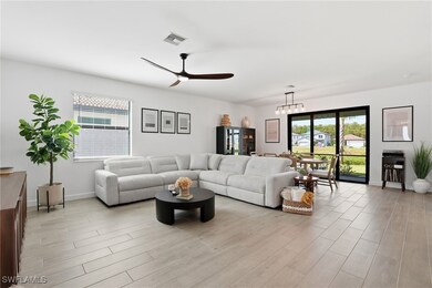 Living area featuring light wood-style flooring, a ceiling fan, and a chandelier