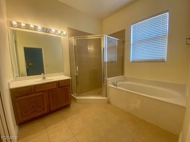 Full bathroom featuring a shower stall, vanity, light tile patterned floors, and a garden tub
