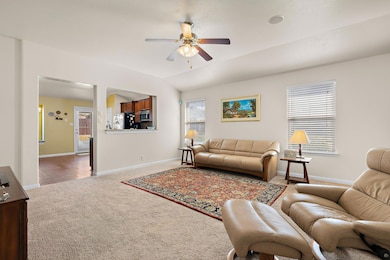 Carpeted living room featuring ceiling fan and lofted ceiling