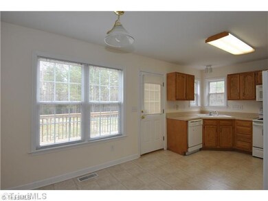 Breakfast. Neutral kitchen/dining area has double windows looking toward deck and woods.