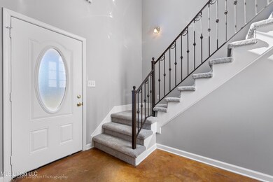 Entry with tall ceilings, wrought iron railing on stairs.