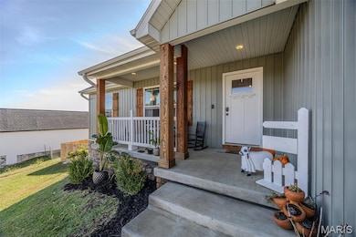 View of exterior entry with covered porch, heating unit, board and batten siding, and a yard