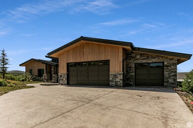 Contemporary home featuring stone siding, driveway, and a garage