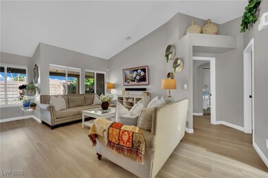 Living area with high vaulted ceiling, light wood-