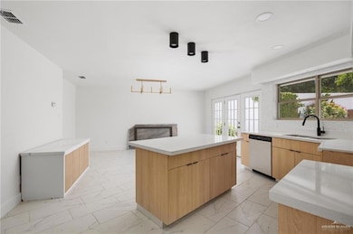 Kitchen with light tile patterned flooring, a center island, sink, and stainless steel dishwasher