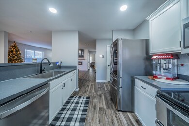 Kitchen with dark countertops, white cabinets, stainless steel appliances, dark wood-style floors, and recessed lighting