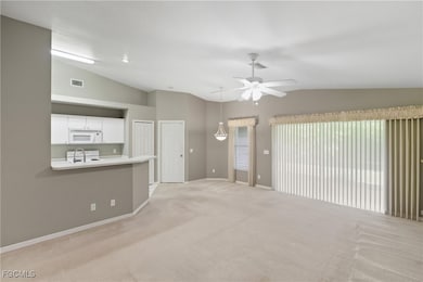 Unfurnished living room featuring vaulted ceiling, light carpet, and ceiling fan