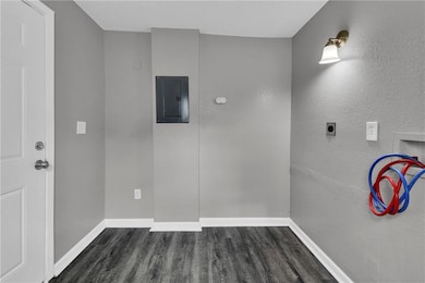 Laundry area with dark wood-type flooring, electric panel, washer hookup, a textured wall, and hookup for an electric dryer