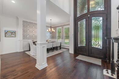 Foyer entrance with ornate columns, french doors, dark wood-type flooring, and a chandelier