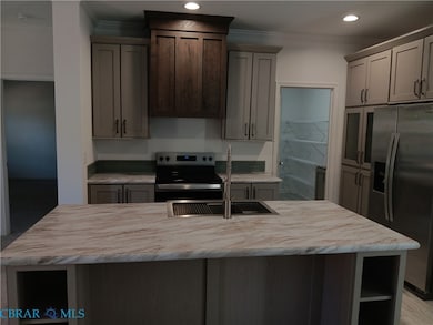 Kitchen featuring open shelves, appliances with stainless steel finishes, gray cabinetry, a kitchen island with sink, and ornamental molding