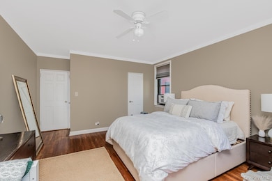 Bedroom with crown molding, a ceiling fan, baseboards, and dark wood finished floors