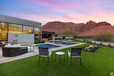 Pool at dusk with an outdoor living space with a fire pit, a patio, a fenced backyard, a mountain view, and a pool with connected hot tub