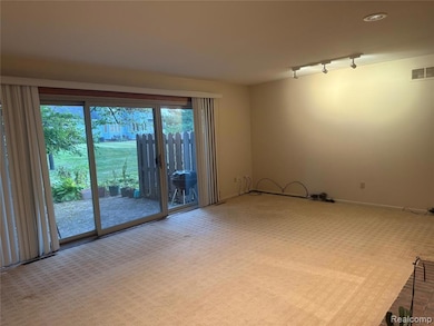 Carpeted spare room featuring track lighting and baseboards