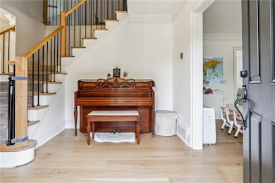 Foyer entrance featuring crown molding, wood finis