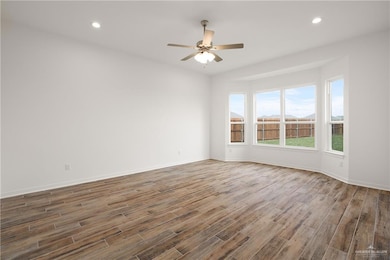 Empty room with wood finished floors, ceiling fan, baseboards, and recessed lighting
