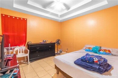Tiled bedroom with a raised ceiling and ceiling fan