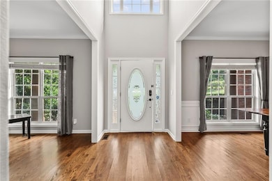 Entrance foyer featuring crown molding, wood finished floors, and baseboards