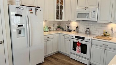 Kitchen with white cabinetry, backsplash, white ap