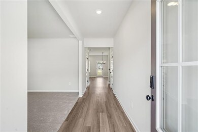 Hall featuring wood finished floors and a chandelier