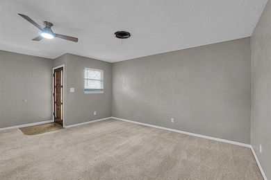 Spare room featuring a textured ceiling, carpet floors, a ceiling fan, and a textured wall