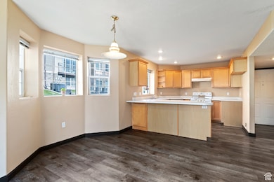 Kitchen with light brown cabinets, light countertops, electric range, open shelves, and a peninsula