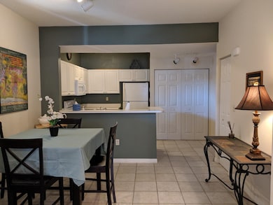 Kitchen with white appliances, white cabinetry, light tile patterned floors, a peninsula, and light countertops