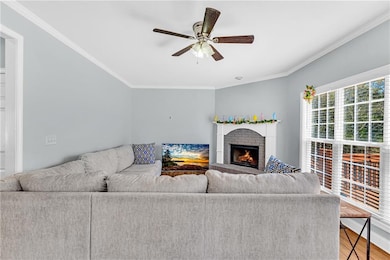 Living area featuring a fireplace, ceiling fan, wo
