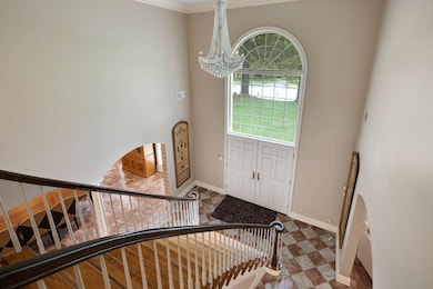 Foyer with a chandelier, baseboards, ornamental molding, and stairway