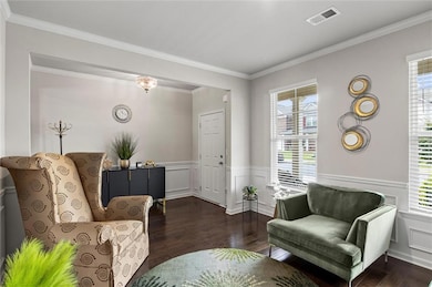 Great room with hardwood finished floors, ample natural light, wainscoting, and ornamental molding
