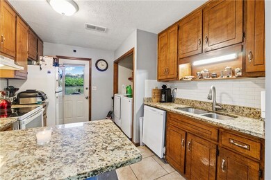 807 Charleston -Kitchen with white appliances, a sink, washer and clothes dryer connections, decorative backsplash, and under cabinet range hood
