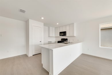 Kitchen with white cabinetry, a peninsula, light wood-type flooring, black appliances, and recessed lighting