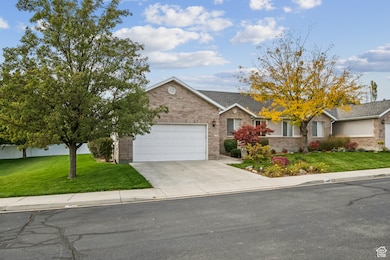 Ranch-style house with a front yard, concrete driveway, brick siding, and a garage
