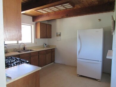 Kitchen with wood ceiling, beam ceiling, white fridge, and light tile patterned floors
