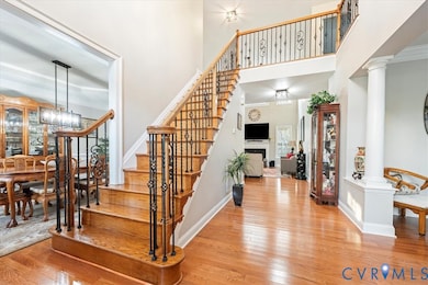 Stairs featuring a chandelier, hardwood / wood-style flooring, ornamental molding, a fireplace, and decorative columns
