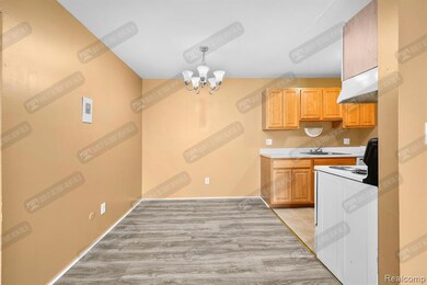 Kitchen with light countertops, white electric stove, a chandelier, and under cabinet range hood