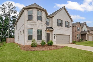 View of front facade featuring driveway, brick siding, and a garage