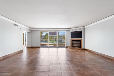Unfurnished living room with crown molding, a fireplace, tile patterned flooring, and baseboards
