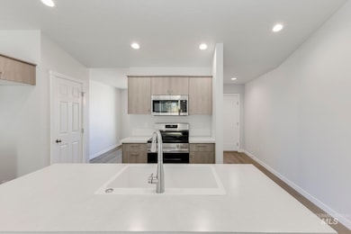 Kitchen featuring stainless steel appliances, light brown cabinetry, recessed lighting, modern cabinets, and wood finished floors