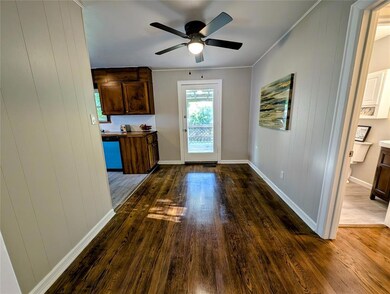 Unfurnished dining area with dark wood finished floors, ceiling fan, baseboards, and crown molding