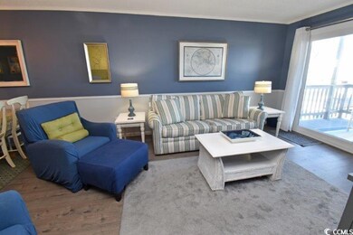 Living area featuring ornamental molding, wainscoting, and wood finished floors
