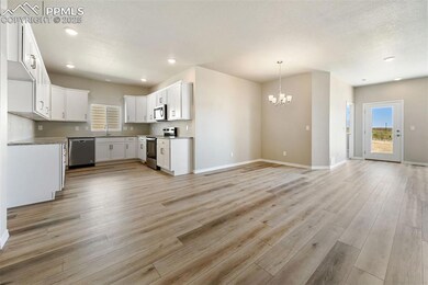 Kitchen featuring appliances with stainless steel finishes, open floor plan, a chandelier, light wood-type flooring, and a sink