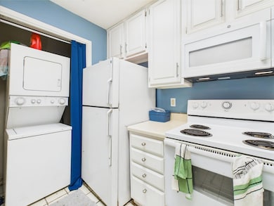 Kitchen with white appliances, estacked washer an