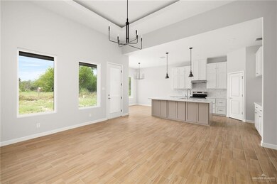 Kitchen with light wood-style floors, tasteful backsplash, light countertops, a sink, and a notable chandelier