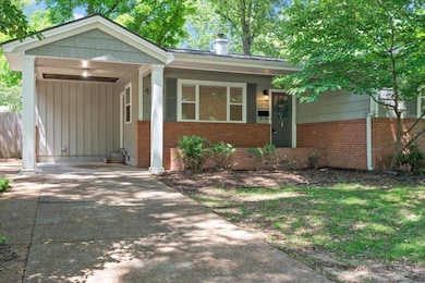 Ranch-style home featuring brick siding, an attached carport, driveway, and a chimney