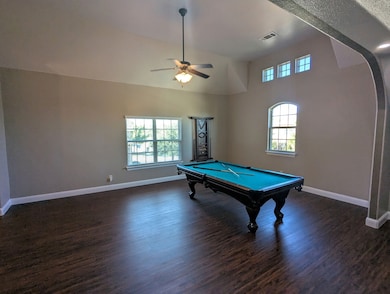 Rec room with conveyed pool table, dark wood finished floors, high vaulted ceiling, plenty of natural light, and a ceiling fan