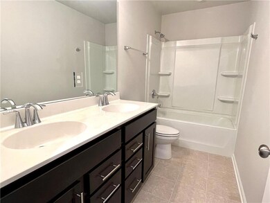 Bathroom featuring double vanity, shower / tub combination, and tile patterned floors