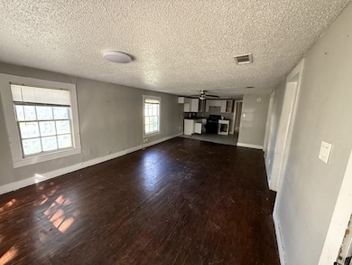 Unfurnished living room featuring dark wood-style flooring, a textured ceiling, and ceiling fan