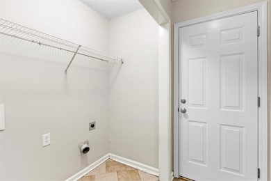 Washroom featuring light tile patterned flooring and electric dryer hookup